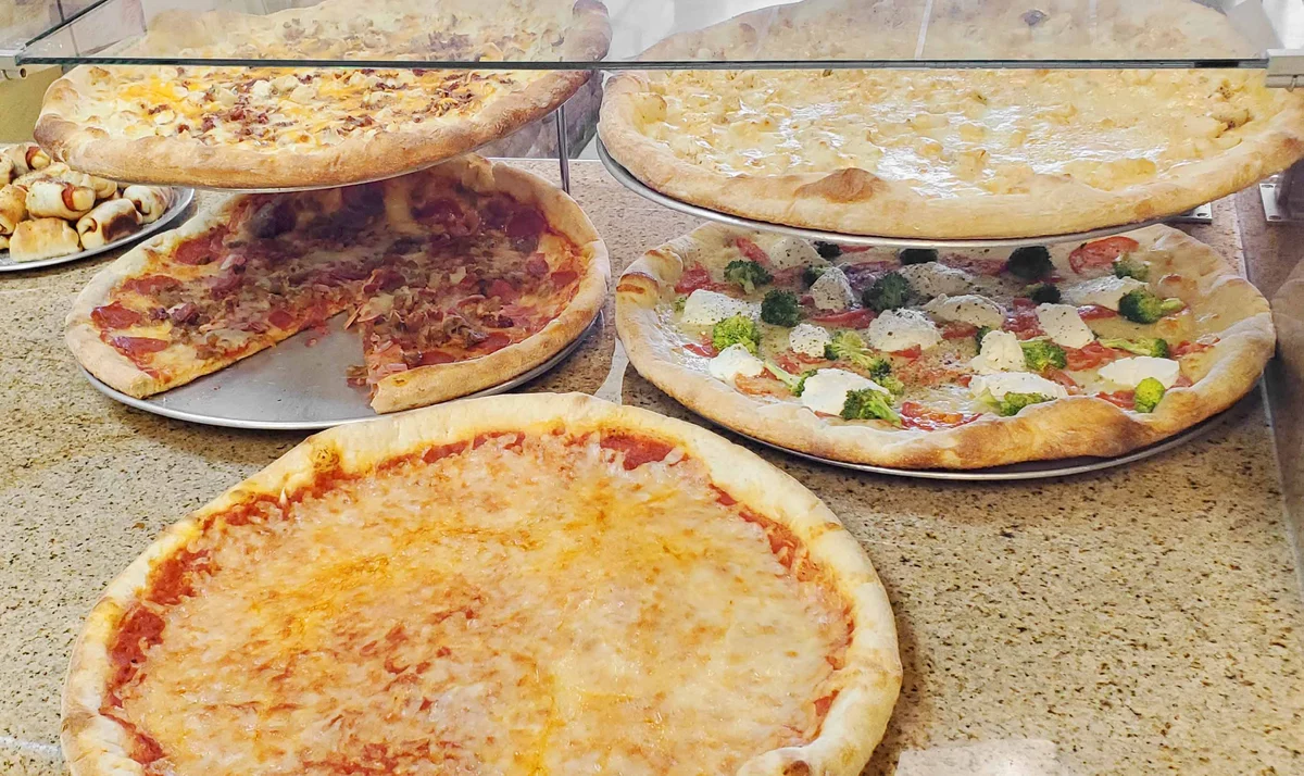 Assorted meat, white and cheese pizzas in the display case at Caretti's